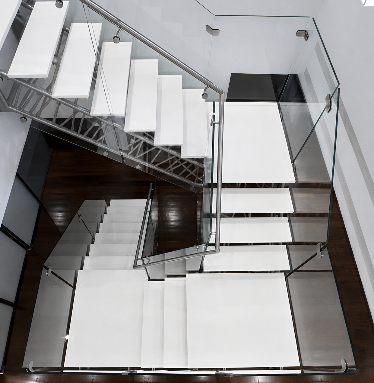 Escalera con peldaños suspendidos en Solid Surface y barandilla de cristal